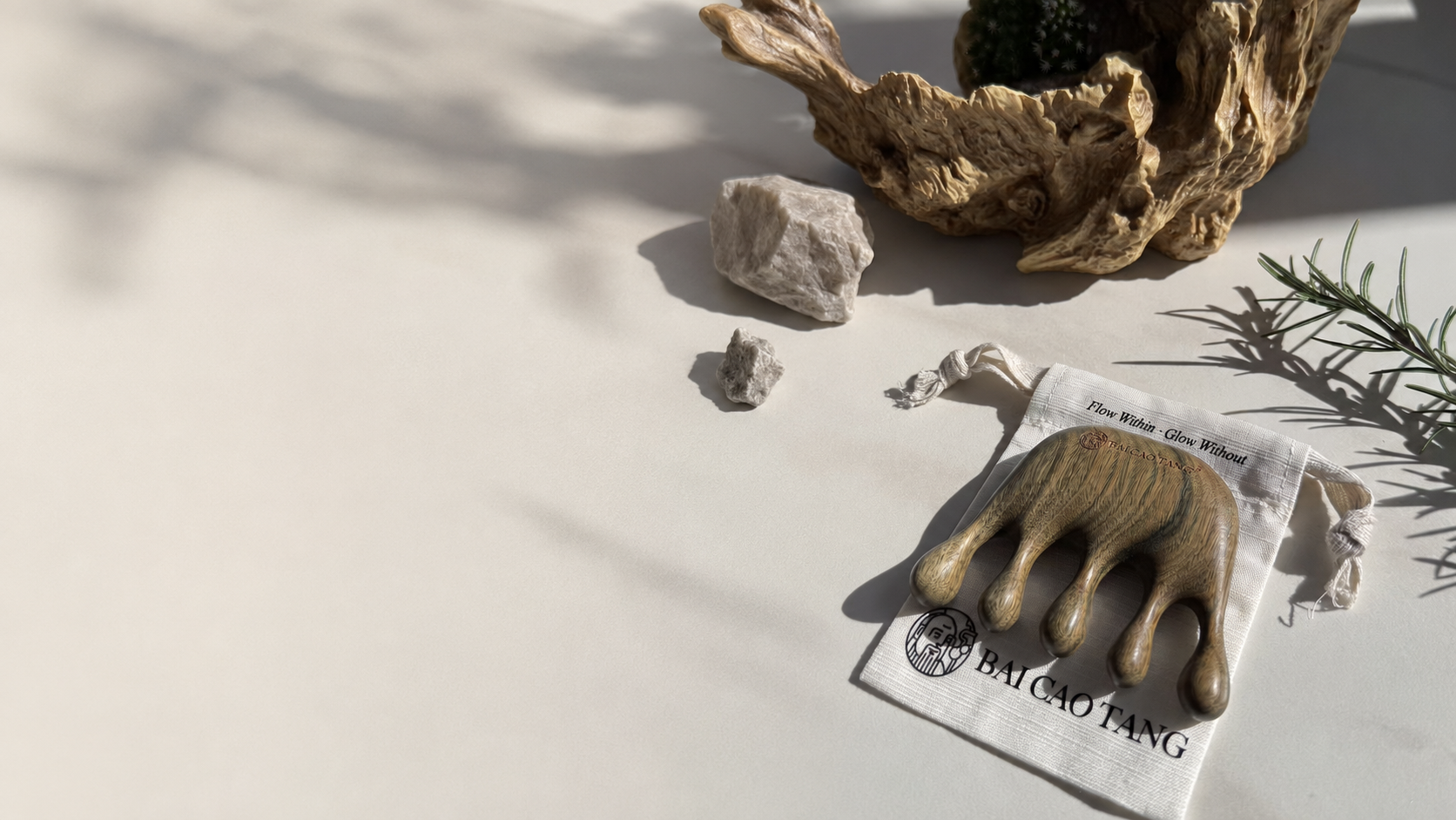 Genuine Bai Cao Tang Green Sandalwood tool on its branded linen pouch in warm natural light.